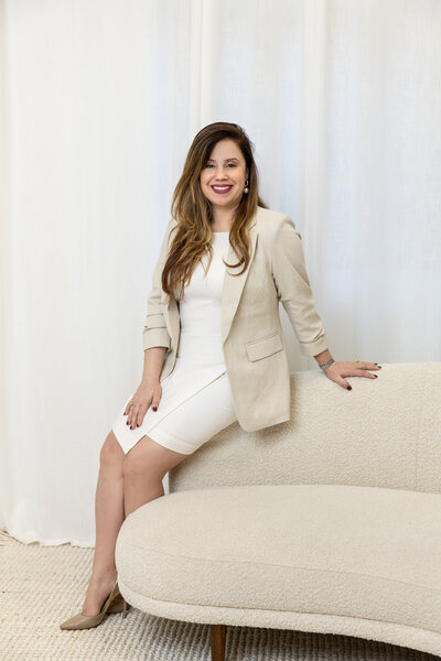 Portrait of Kathy Gladys Colon, founder and CEO of Nova Lux DR Properties, seated on a light sofa
