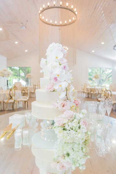 wedding cake on a table decorated with florals and drinking glasses