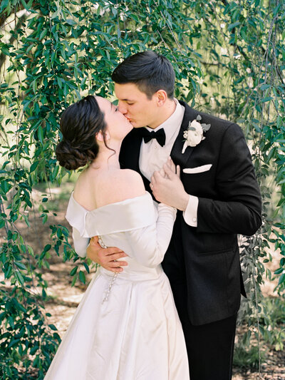 Bride and groom kiss under a tree photographed with film