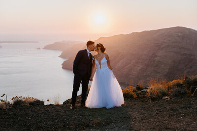 Santorini Elopement couple standing on a mountain during sunset