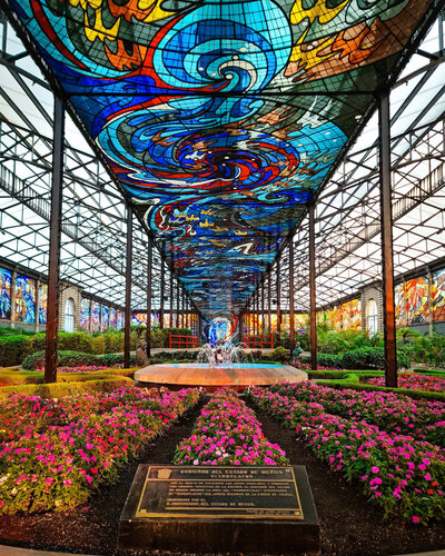 A large strip of stained glass in the glass ceiling of a garden