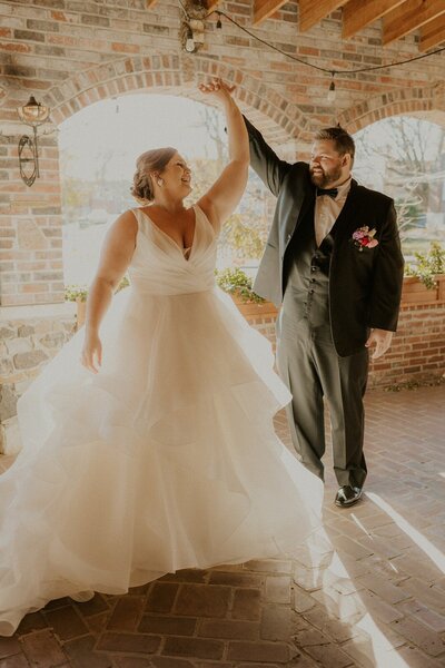 bride and groom posing for their wedding photos while groom  swaying the bride outside the century room at gribic events in st. louis