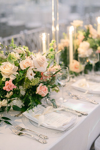 Une table bien décorée dans la salle de réception, avec des fleurs et des chandelles.