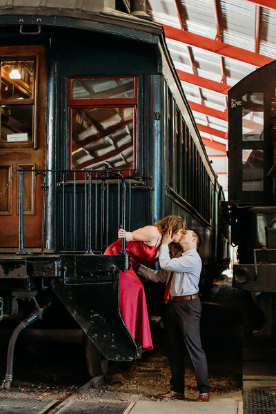 Engaged couple kisses by vintage train