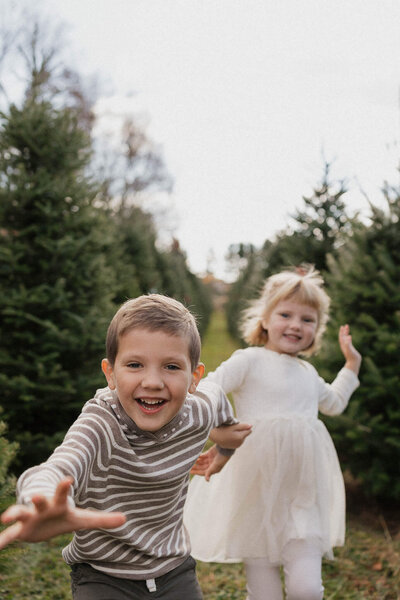 Siblings laughing and running at a Sugar Pines Farm in Chesterland. Playful and candid family photography in Cleveland.