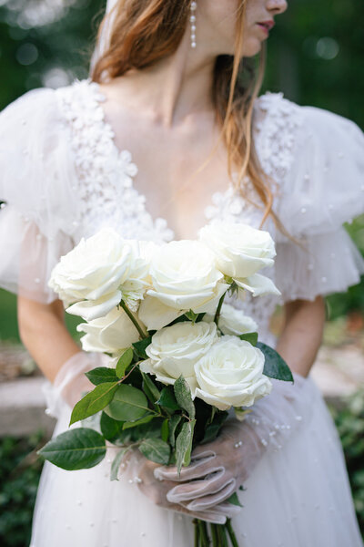 Girl holds white roses while posing for a wedding