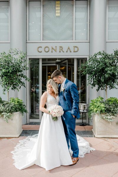 bride and groom snuggled in front of conrad hotel