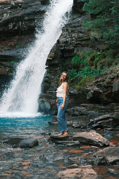 Photographer setting up a wedding details shot at North Star Gatherings in the Colorado mountains, hanging bridal shoes on string lights with a veil draped over her arm.