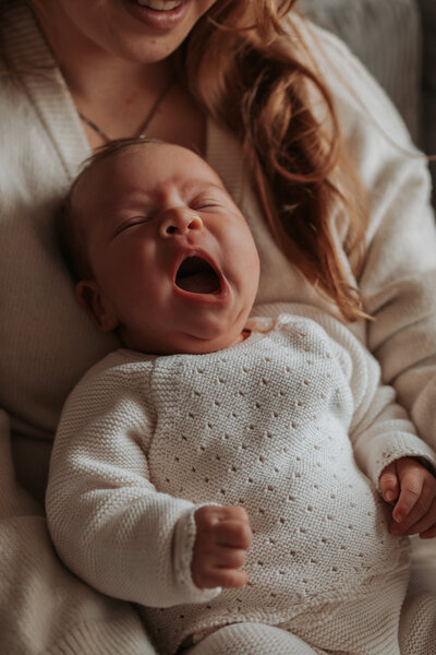Een huilende baby in een wieg, met een liefdevol stel dat poseert in de nabijheid.