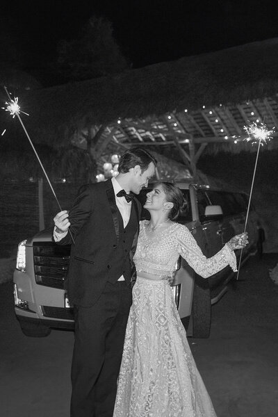 Bride and groom holding sparklers during nighttime wedding exit at Three Bells Mission in Wallis, Texas captured in black and white