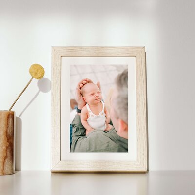 newborn photographer in Springfield Mo The XO Photography captures framed photo of baby boy in dads arms on shelf