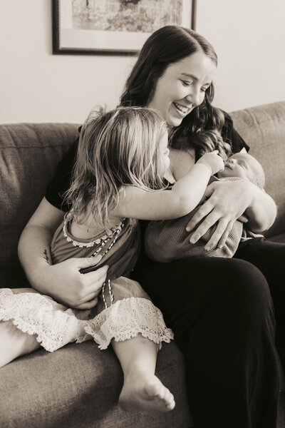 Birth and lifestyle newborn photographer in Tifton Georgia: mother and young girl smiling and admiring newborn sibling