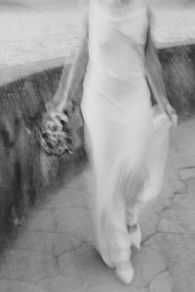 blurry photo of bride walking with her train in one hand and bouquet in the other hand