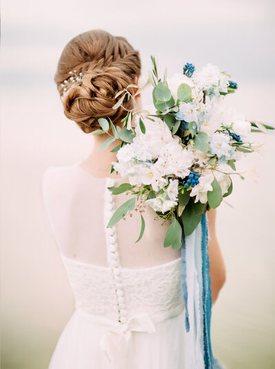 A bride holds her bouquet over her shoulder in an artistic bridal portrait.