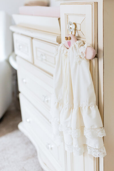 christening gown hangs in nursery