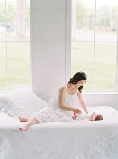 Mother and baby white linens on bed taken by Denver Family Photographer
