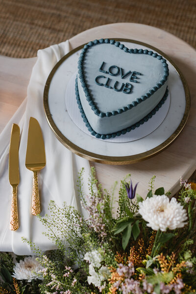 Love Club cake on table surrounded by flowers