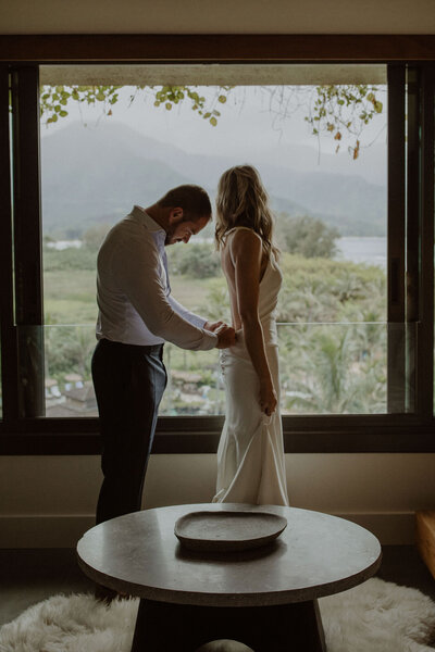 Groom buttons up bride's dress in the 1-Hotel Hanalei