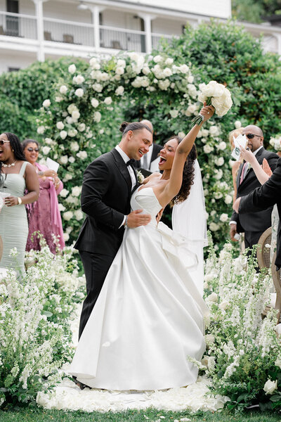 Groom embraces his bride who holds her wedding bouquet