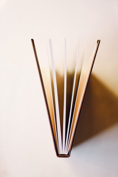 A brown leather wedding album with flat lay photos of the bride and groom's wedding day, standing upright with the pages slightly opened.