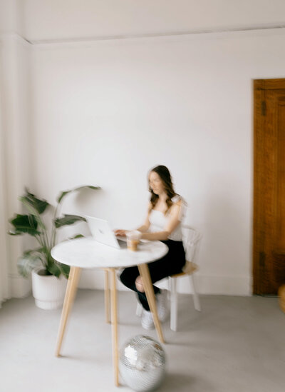 Showit website designer sitting at a desk with her laptop