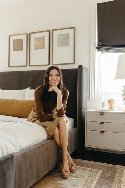 Hope Danyla, owner of Hope Miriam Designs, sitting with her feet up in a chair in a warm toned room