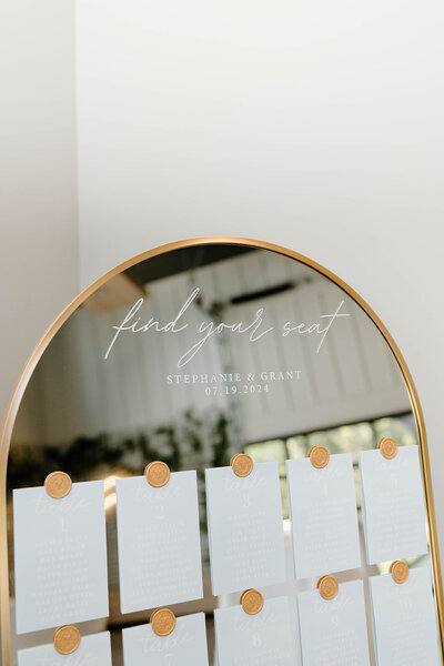 Beautiful wedding seating chart displayed on a mirror, featuring guest names and elegant calligraphy, adding a stylish touch to the reception in Columbus, OH.