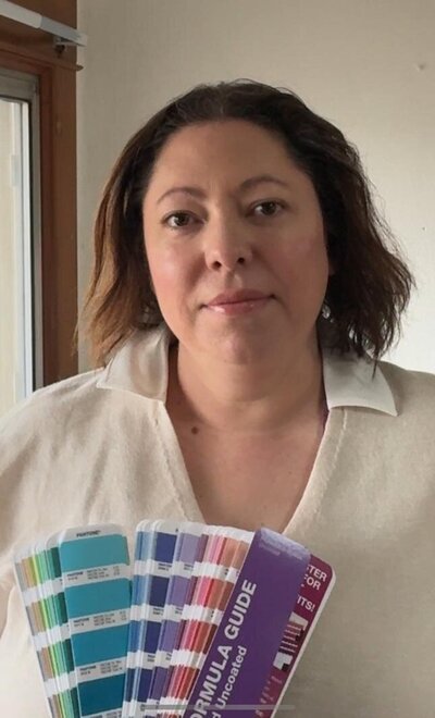 headshot of company owner, brunette woman holding a Pantone system color fan deck