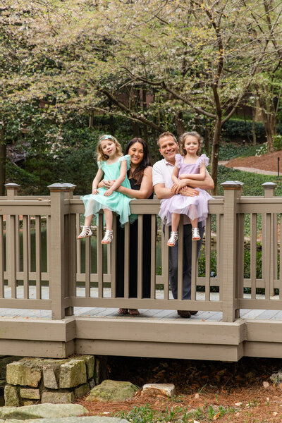 Family standing on a bridge in a park during photo session by Laure Photography