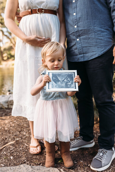 Maternity Photographer, a  little girl holds a picture of her sibling-to-be in an ultra sound