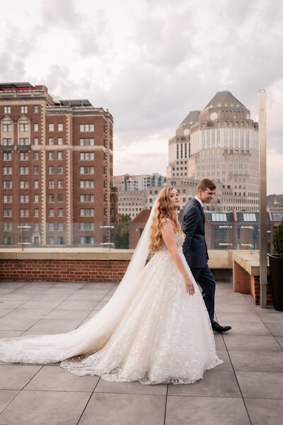 Jada and Michael pose on the grand staircase of the Monastery Event Centre, their figures framed by the intricate architecture, highlighting the grandeur and romance of their wedding day.
