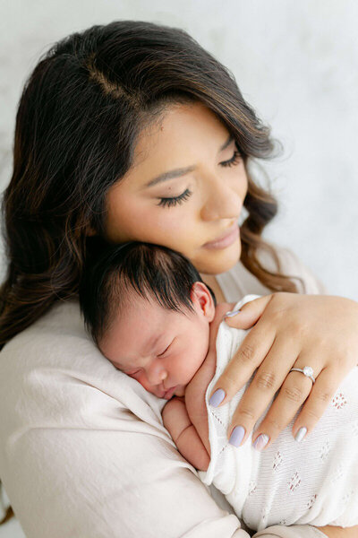 Professional San Francisco Bay Area newborn photography with mom cuddling newborn against chest.