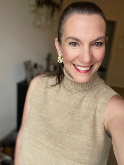 chasity campbell smiling at camera with taupe sleeveless turtlenck red lips and slicked back pony