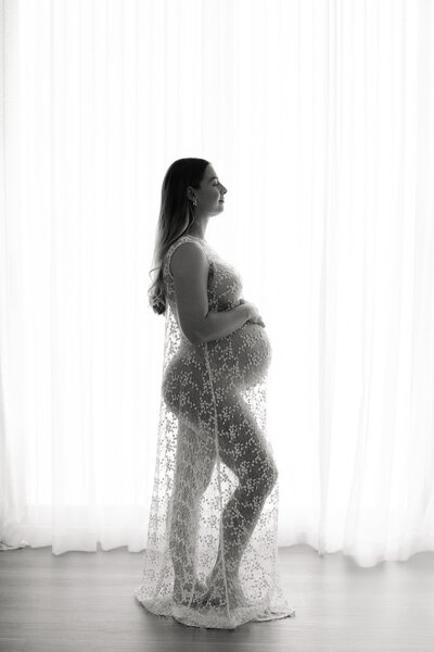 Pregnant woman looking down at her belly sweetly in pregnancy photo studio
