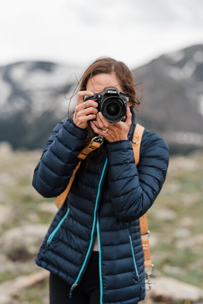 A photo of a woman taking a photo with mountains behind her