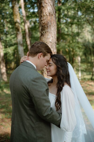 romantic photo of groom kissing bride's forehead while she has her eyes closed