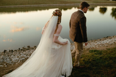 candid wedding photo of a couple walking by a lake in the eveing