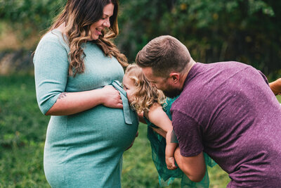 maternity photo with toddler kissing pregnant mom belly