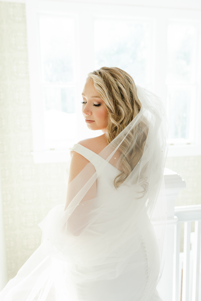 Bride with veil wrapped around waist looking back over her shoulder