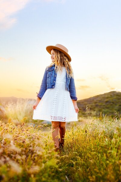 Young girl walking through a field in San Diego with mountains in the backgrounf