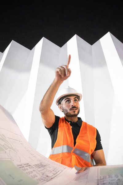 Construction team leader pointing upward with blueprint in hand, symbolizing vision and growth-oriented leadership