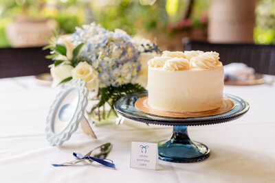 Blue and white hydrangeas flowers with white cake on navy pedestal for table centerpieces.
