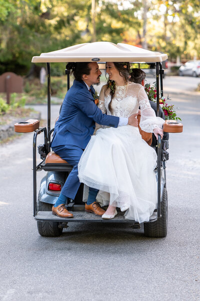A wedding couple about to kiss in the back of a golf cart 