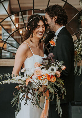 Special moment between bride and groom, bride holding her gorgeous peach and green bouquet thats full of texture