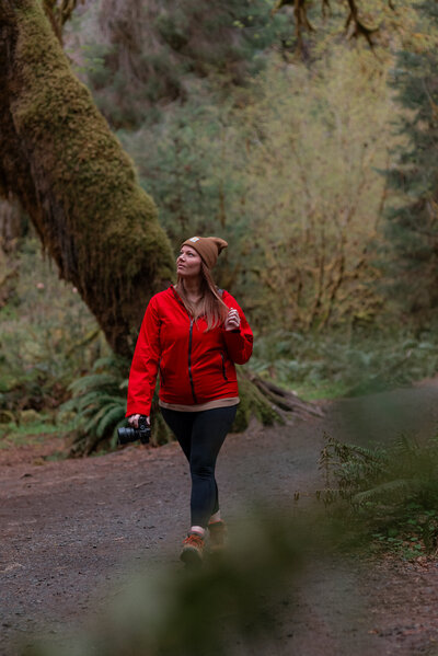 girl walks through forest holding camera