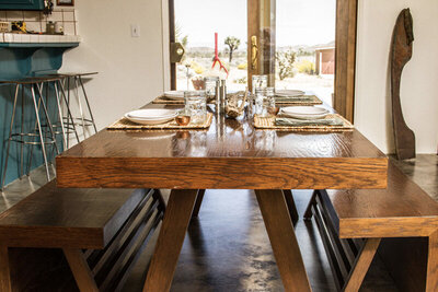 Destination branding Gatos Trail Ranch indoor dining table set with glasses plates patio doors to desert in background
