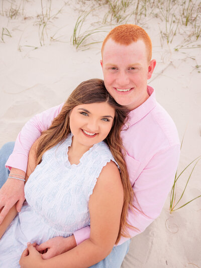 Couple sitting in an embrace at Gulf Shores Pavilion on sand dunes