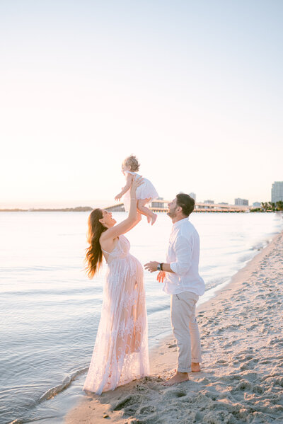 Dad and mom throwing toddler in the air during sunset by Miami Maternity Photographer