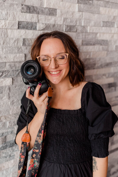 Woman poses for the camera with Nikon Z6II Camera held against her cheek.