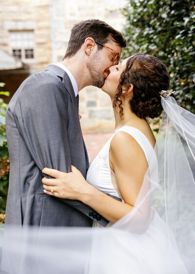 Bride and groom sharing a passionate kiss in a lush Raleigh garden, romantic wedding portrait